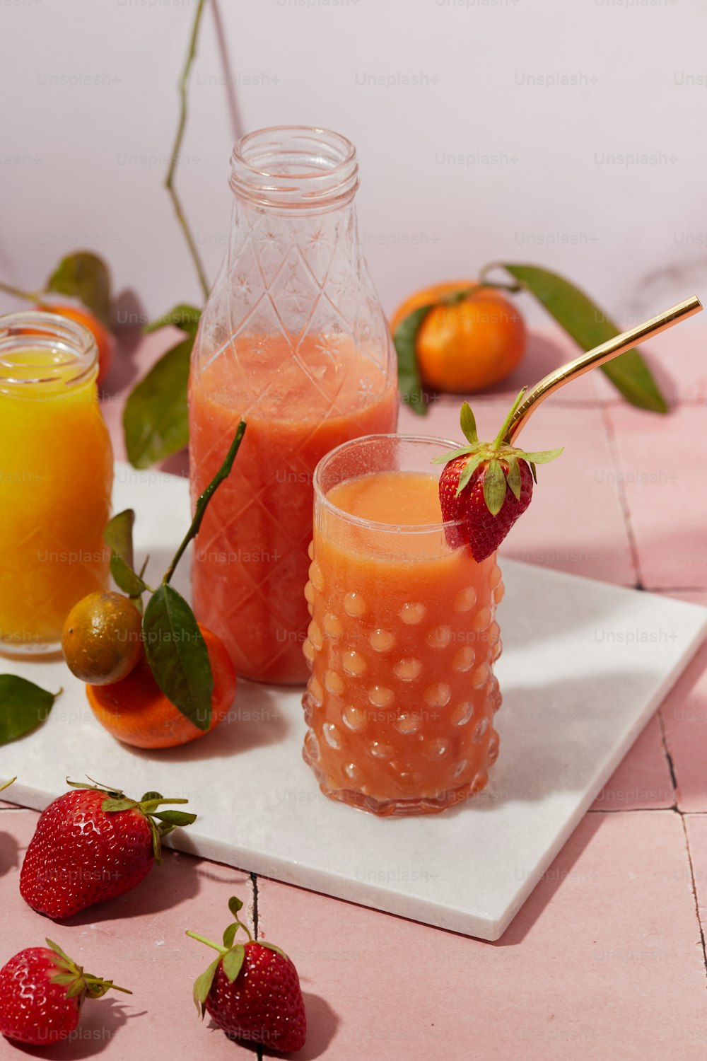 a table topped with two glasses of juice and strawberries