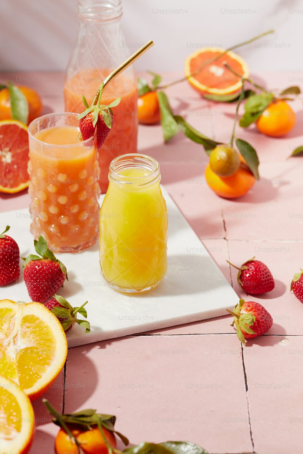 uma mesa coberta com laranjas, morangos e um frasco de líquido