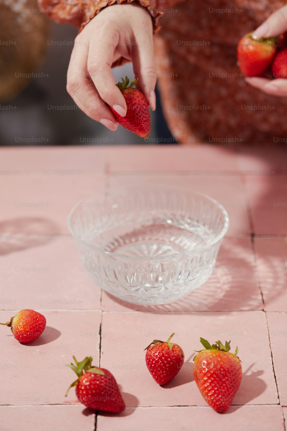 Une femme cueille des fraises dans un bol