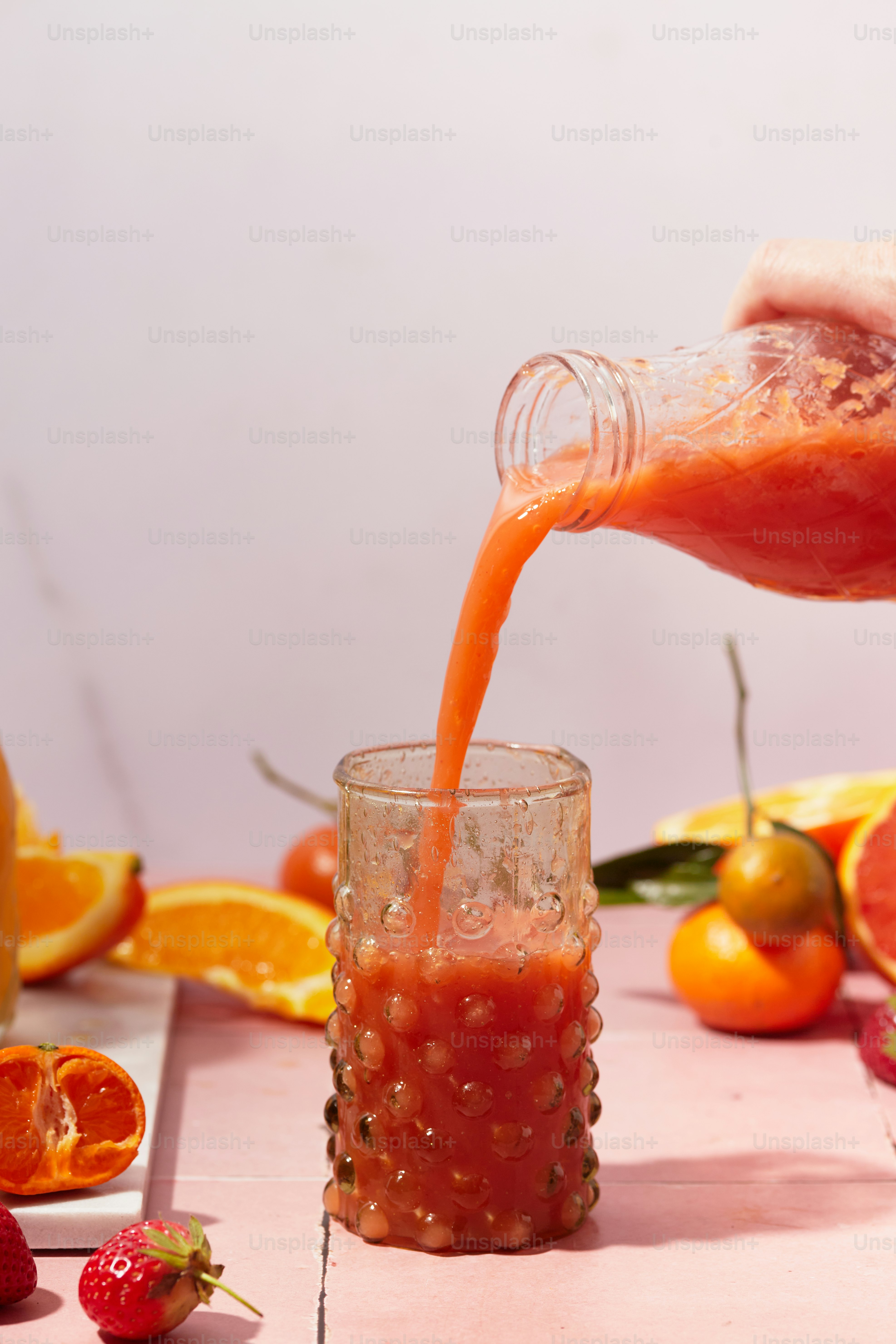 a person pouring orange juice into a glass