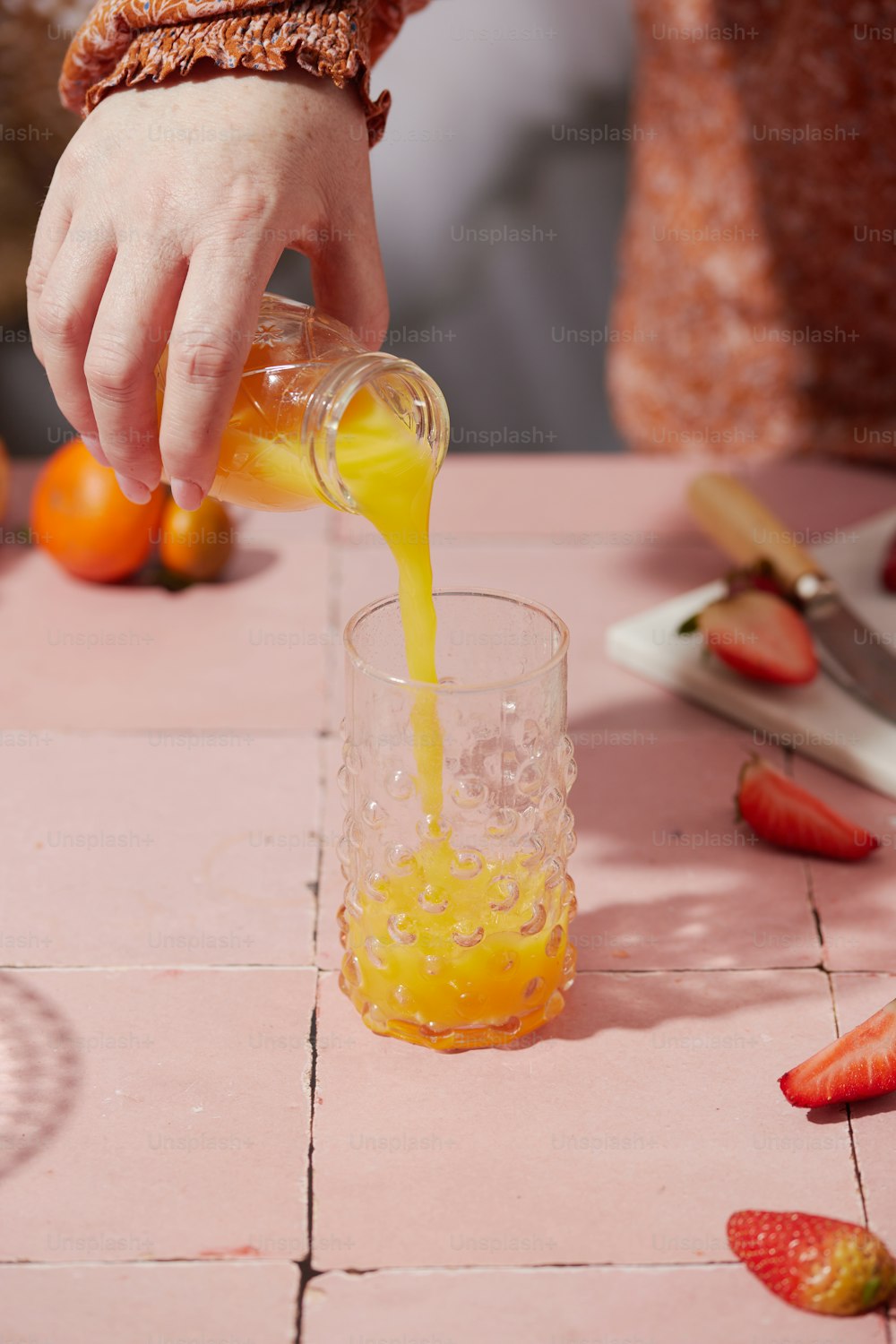 a person pouring orange juice into a glass