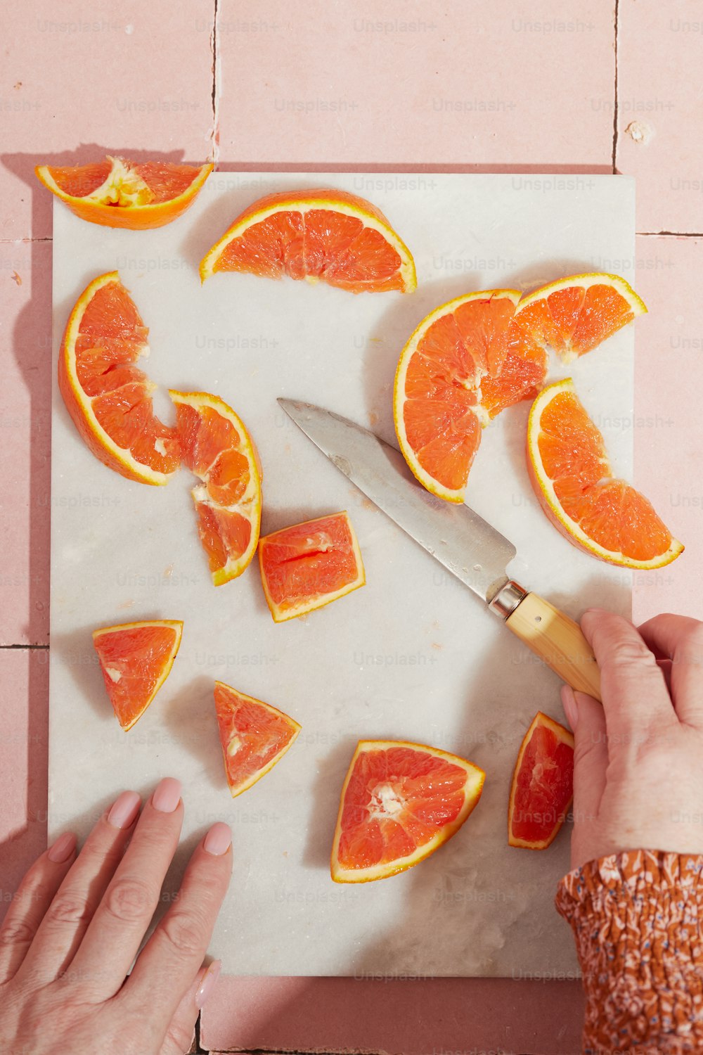 uma pessoa cortando fatias de laranja em uma tábua de corte