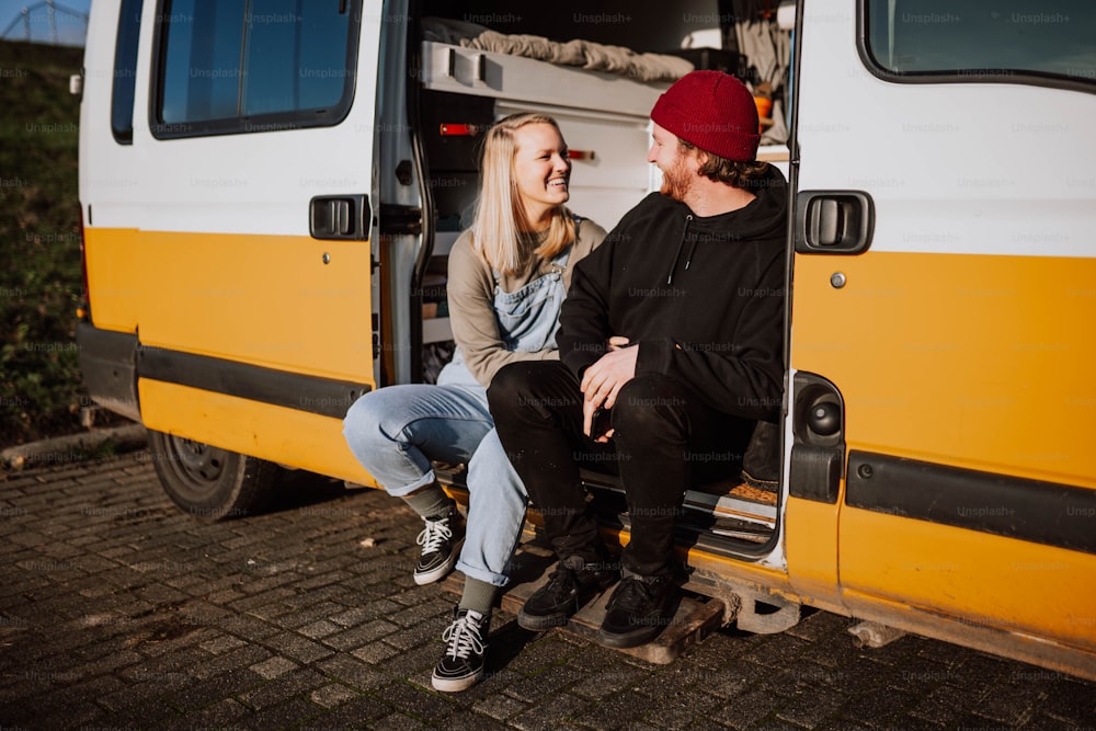 a man and a woman sitting in the door of a van
