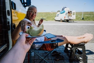 a woman sitting in a chair next to a man holding a plate