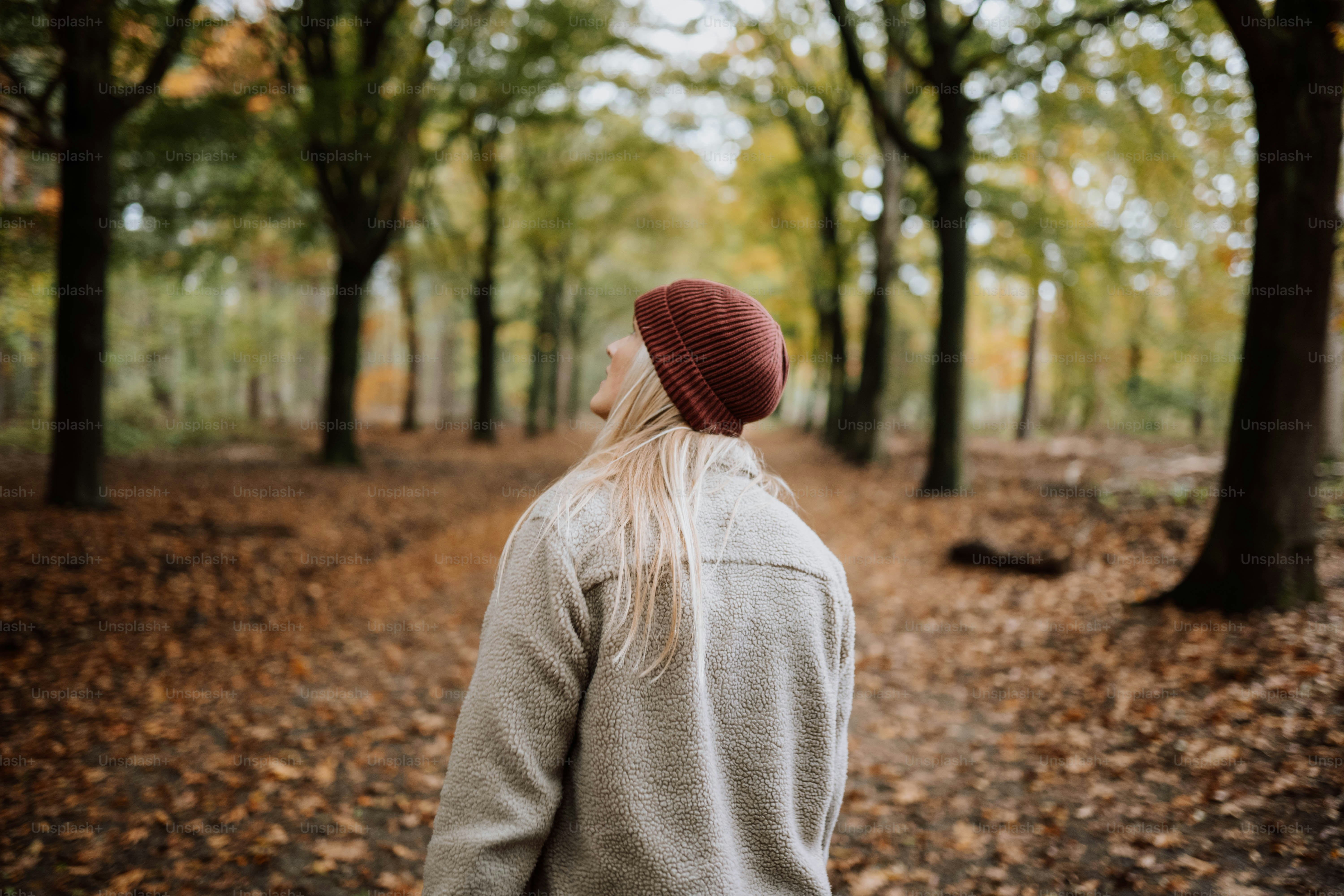 a woman in a red hat is walking through the woods