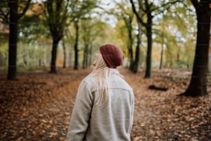 a woman in a red hat is walking through the woods