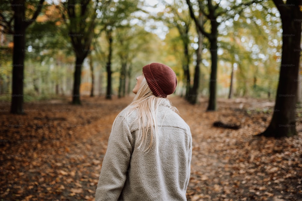 Una mujer con sombrero rojo camina por el bosque