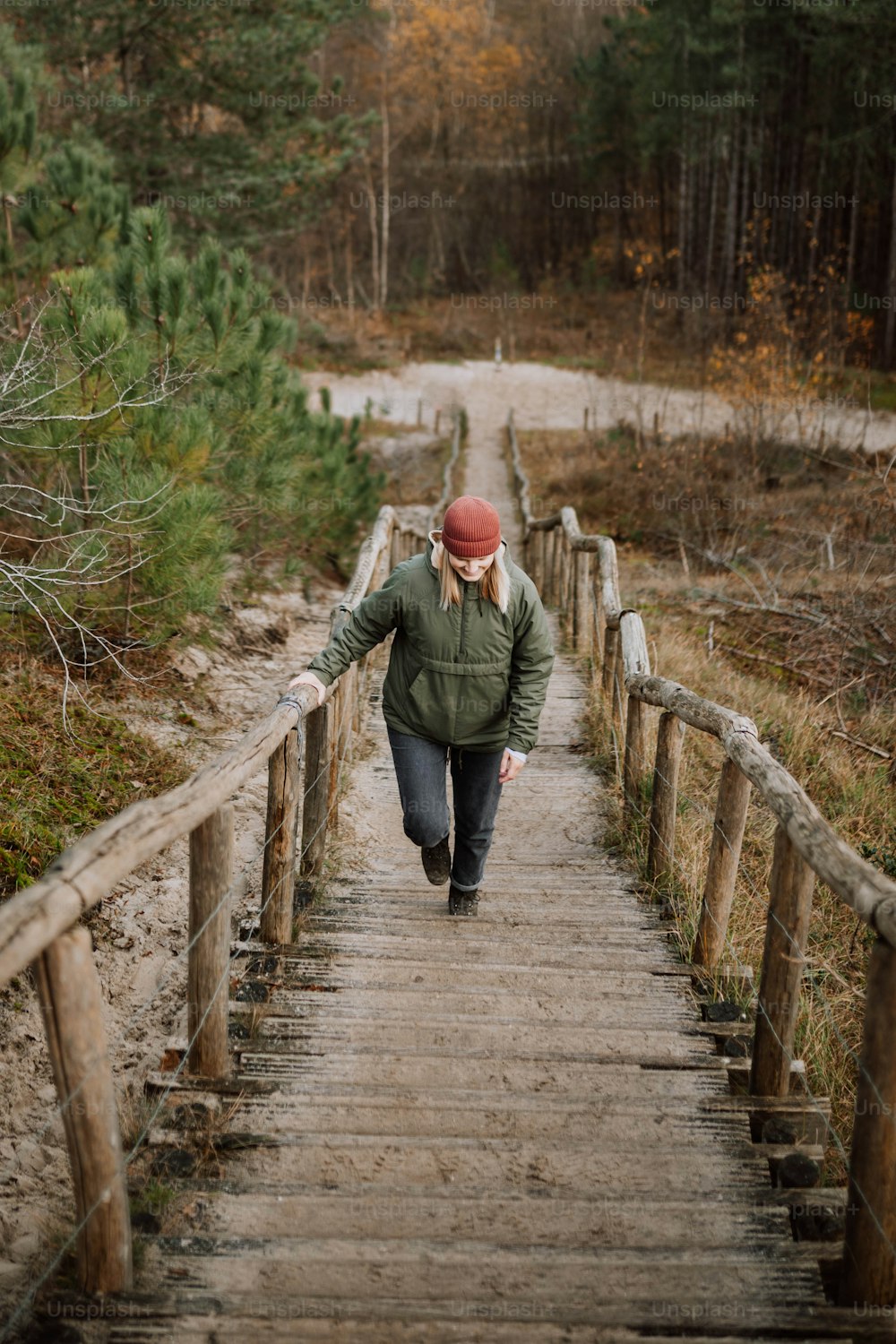 a woman walking down a wooden bridge in the woods