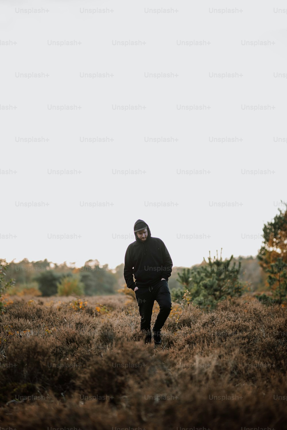 a man in a black jacket walking through a field