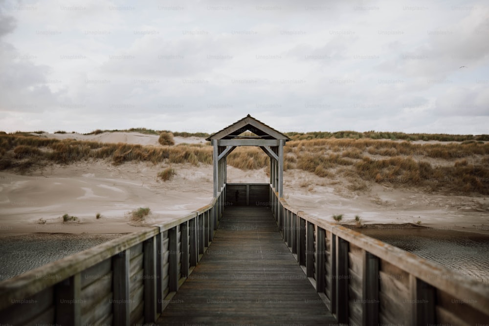 Una passerella di legno che conduce a una spiaggia con dune di sabbia sullo sfondo