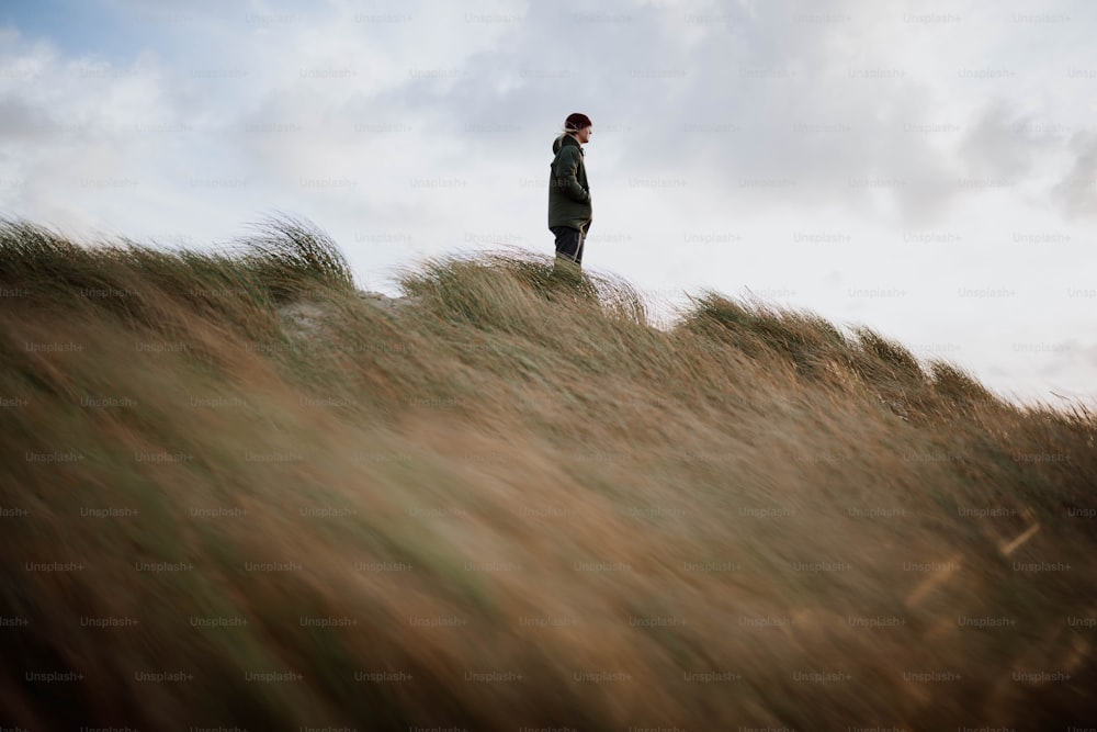 Un homme debout au sommet d’une colline couverte d’herbe