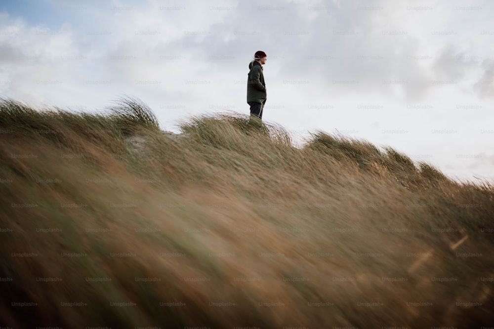 a man standing on top of a grass covered hill