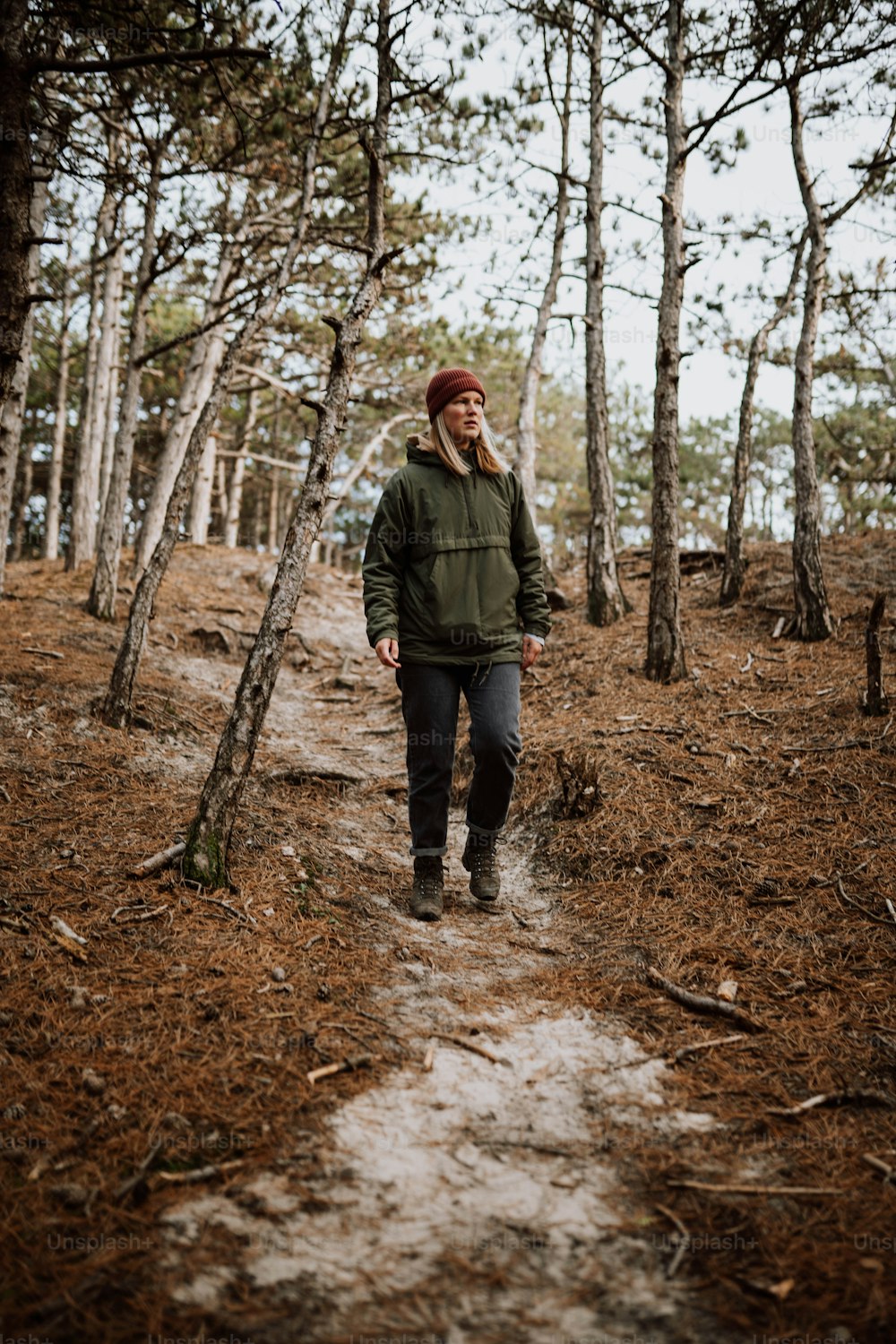 a man in a green jacket is walking through the woods