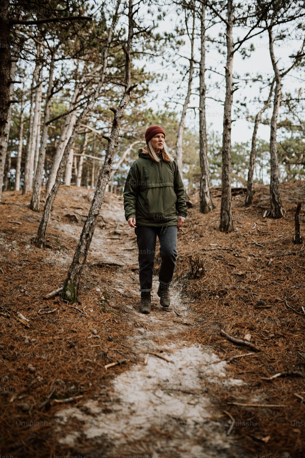 緑のジャケットを着た男が森の中を歩いている
