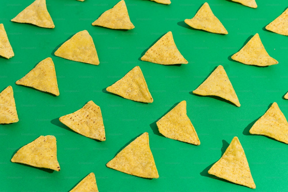 Un grupo de chips de tortilla sentados encima de una superficie verde