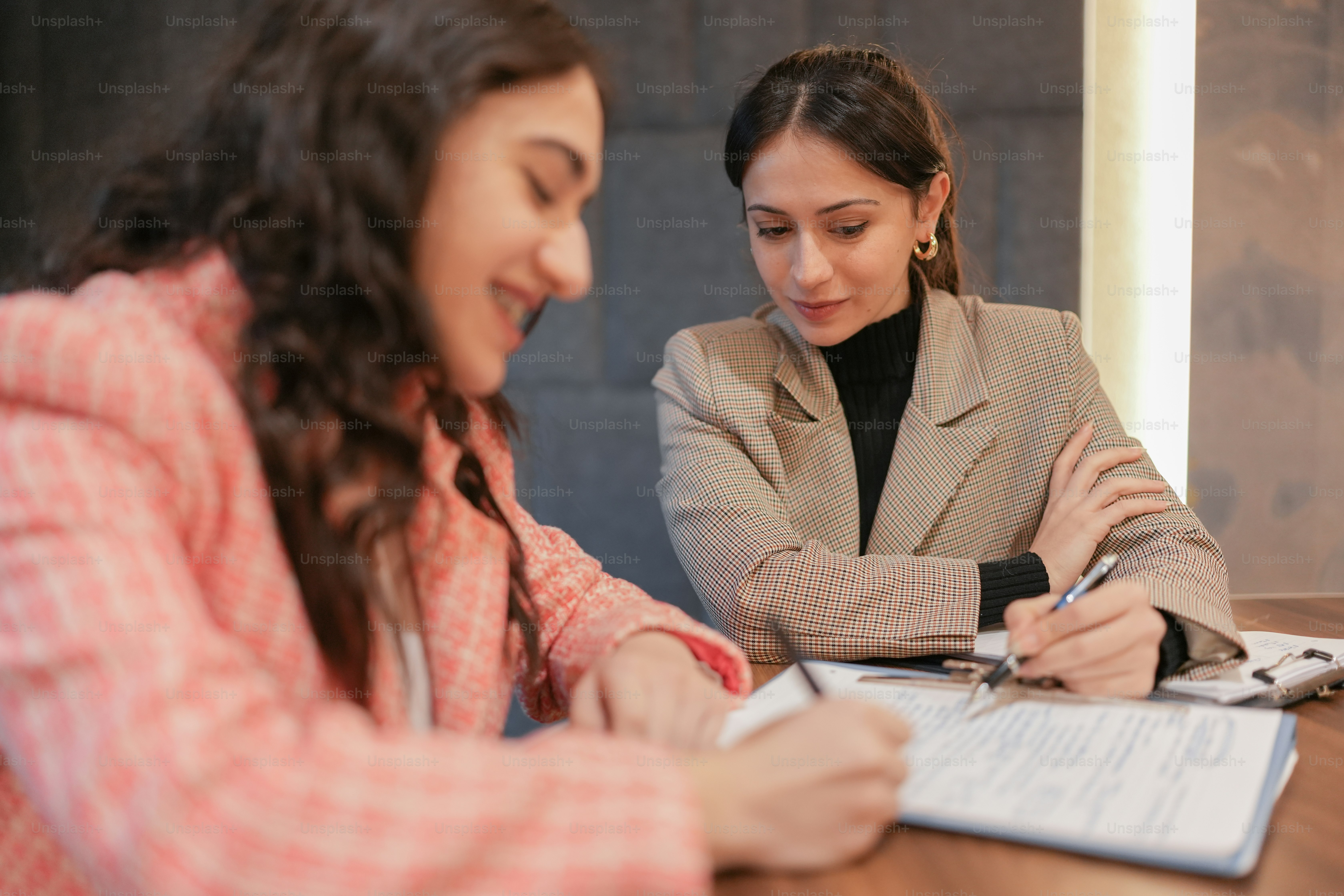 two women sitting at a table signing papers