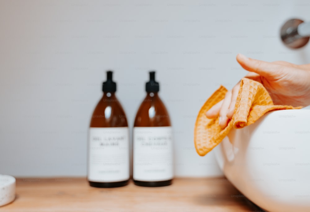 a person holding an orange peel in front of two bottles of hand sanitizer