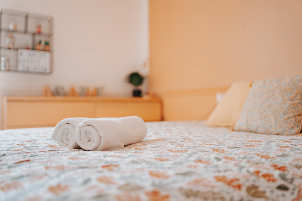 uma toalha branca enrolada sentada em cima de uma cama