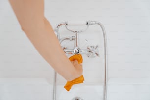 uma pessoa está limpando uma banheira com um pano