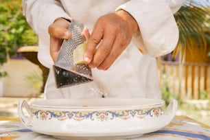 Un chef rallando algo en un plato con un rallador