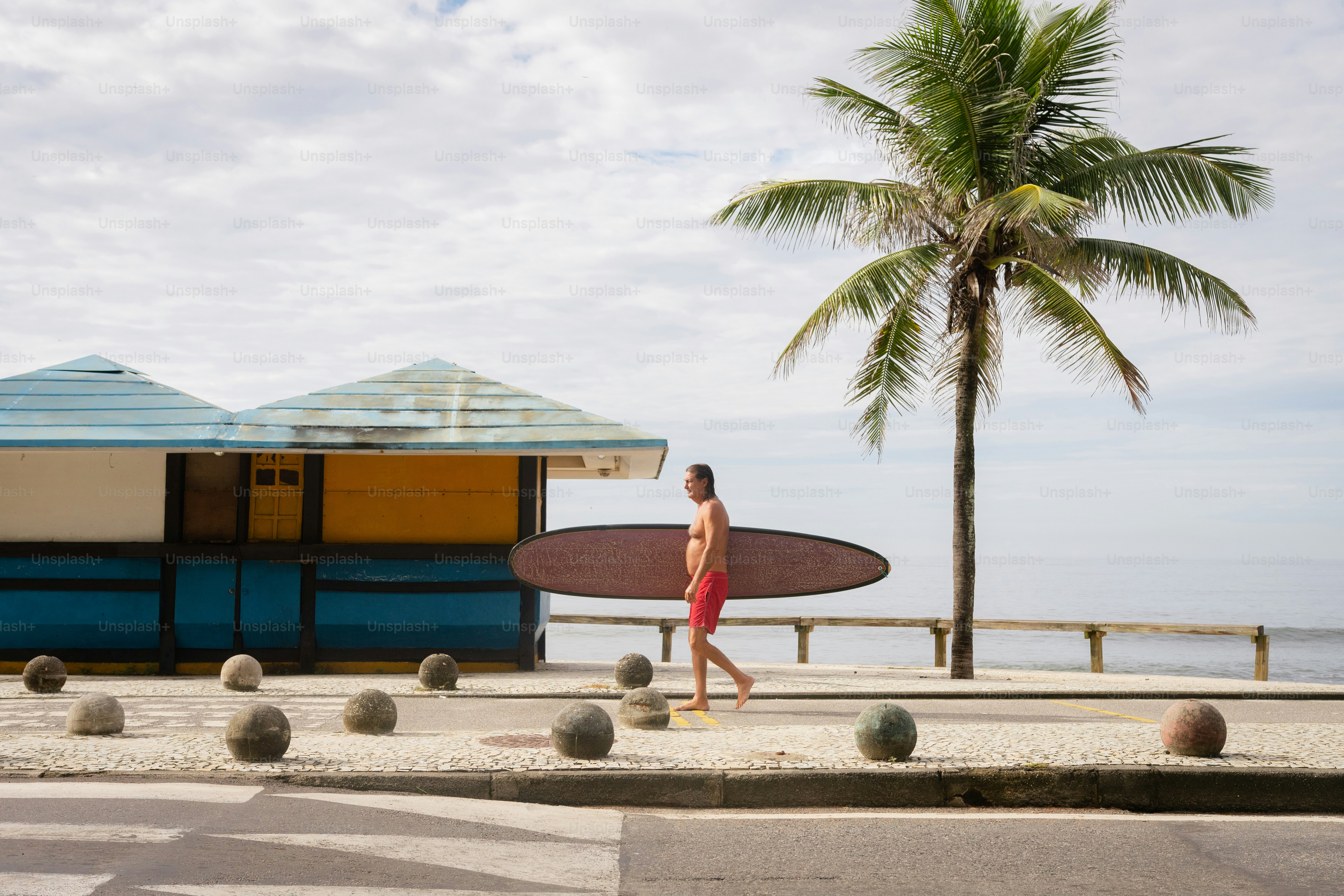 a man with a surfboard walking down the street