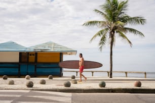 a man with a surfboard walking down the street