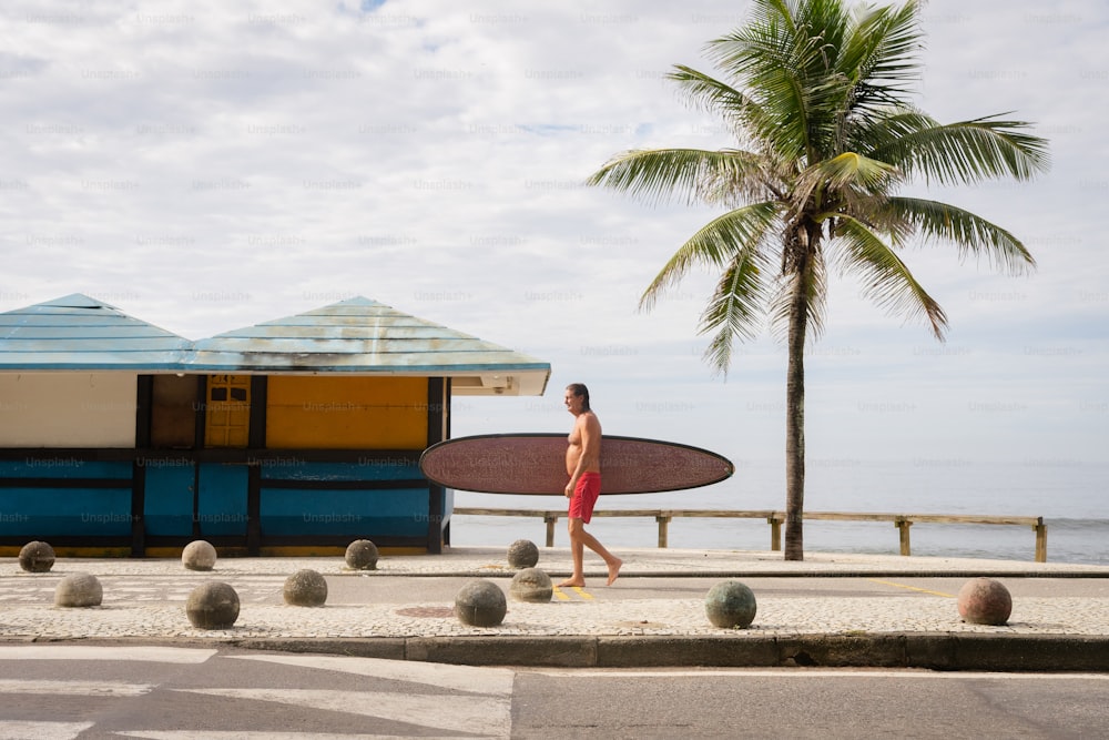 a man with a surfboard walking down the street