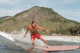 Un hombre montando una tabla de surf encima de una ola