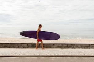 Un hombre caminando por la calle con una tabla de surf