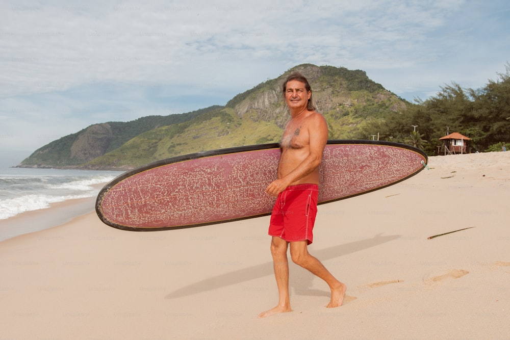 um homem segurando uma prancha de surf em uma praia