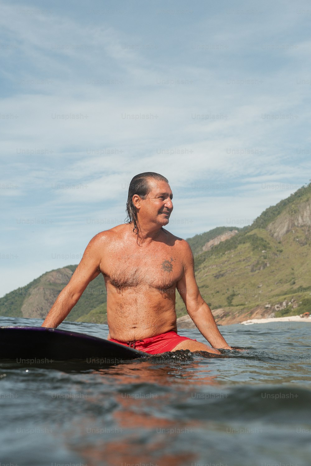 Un hombre sin camisa montando una tabla de surf en un cuerpo de agua
