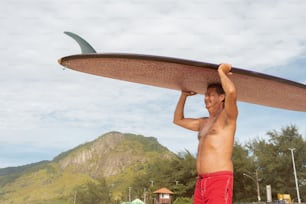 Un hombre sosteniendo una tabla de surf sobre su cabeza
