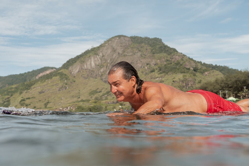 Un hombre tumbado en una tabla de surf en el agua