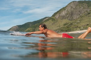 um homem deitado em cima de uma prancha de surf no oceano