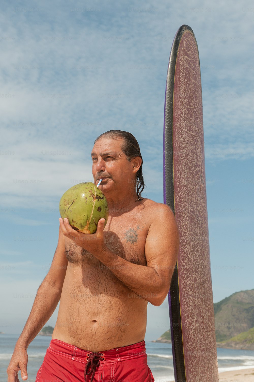 a man standing on a beach next to a surfboard