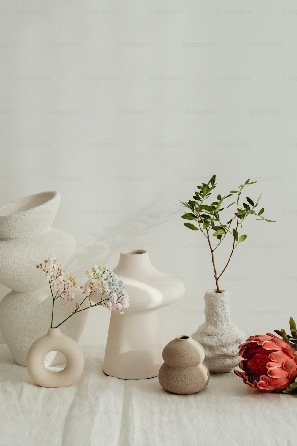 Una mesa blanca cubierta con jarrones llenos de flores