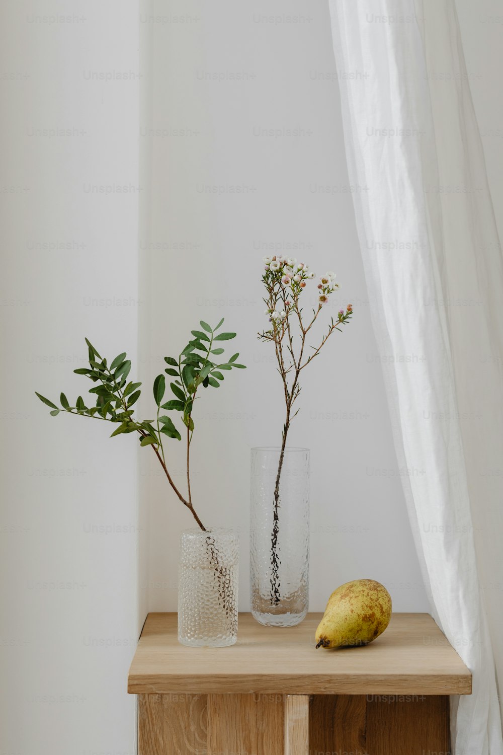 a wooden table topped with two vases filled with plants