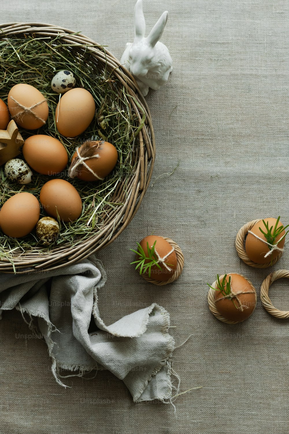 a basket filled with brown eggs next to a white bunny