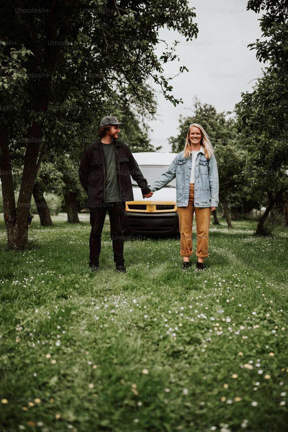 a man and a woman holding hands in front of a car