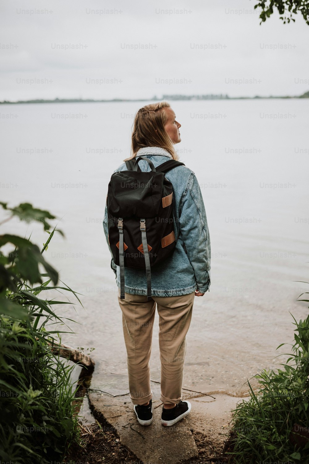 uma mulher com uma mochila olhando para a água