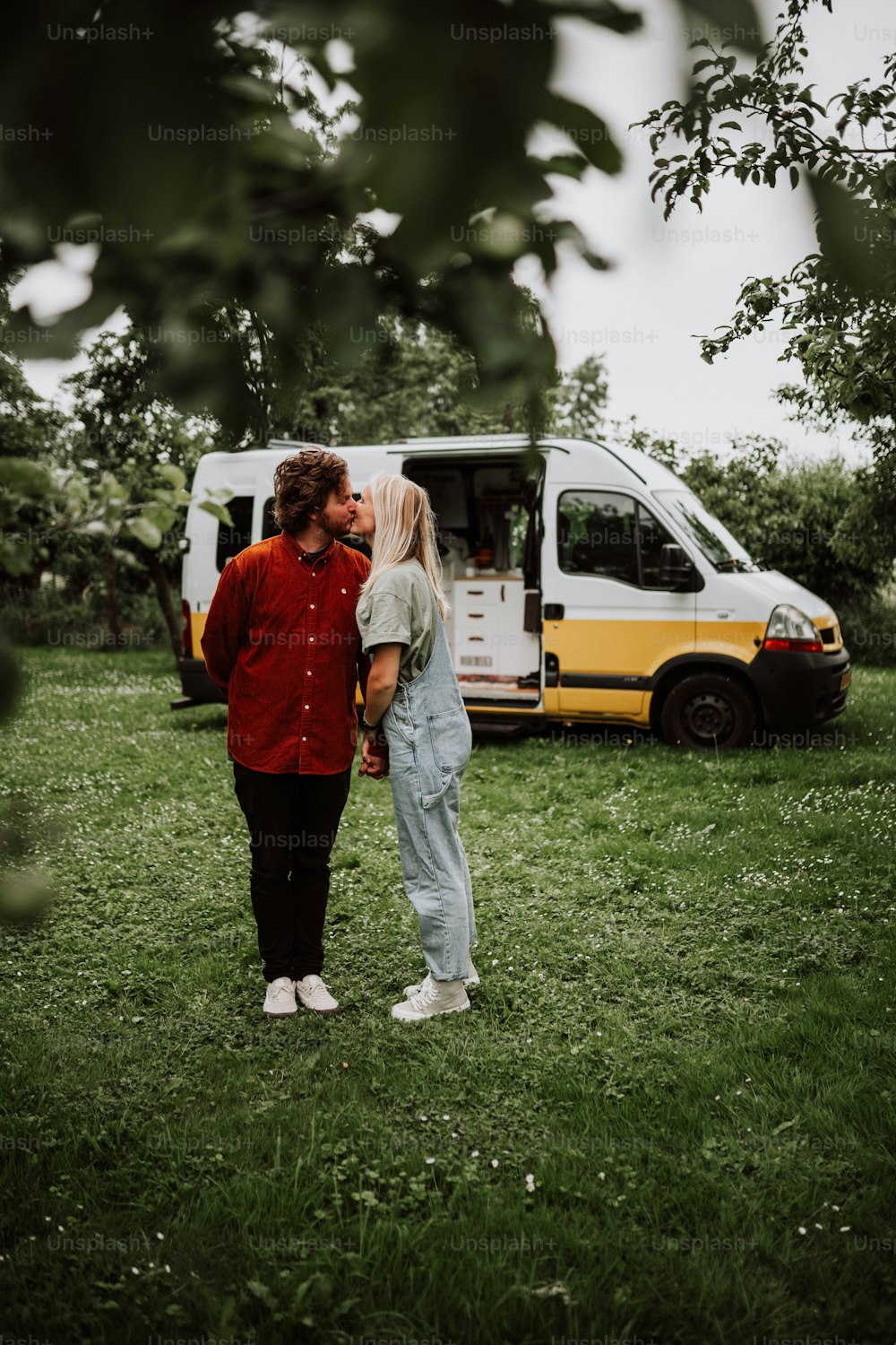 a man and a woman kissing in front of a van