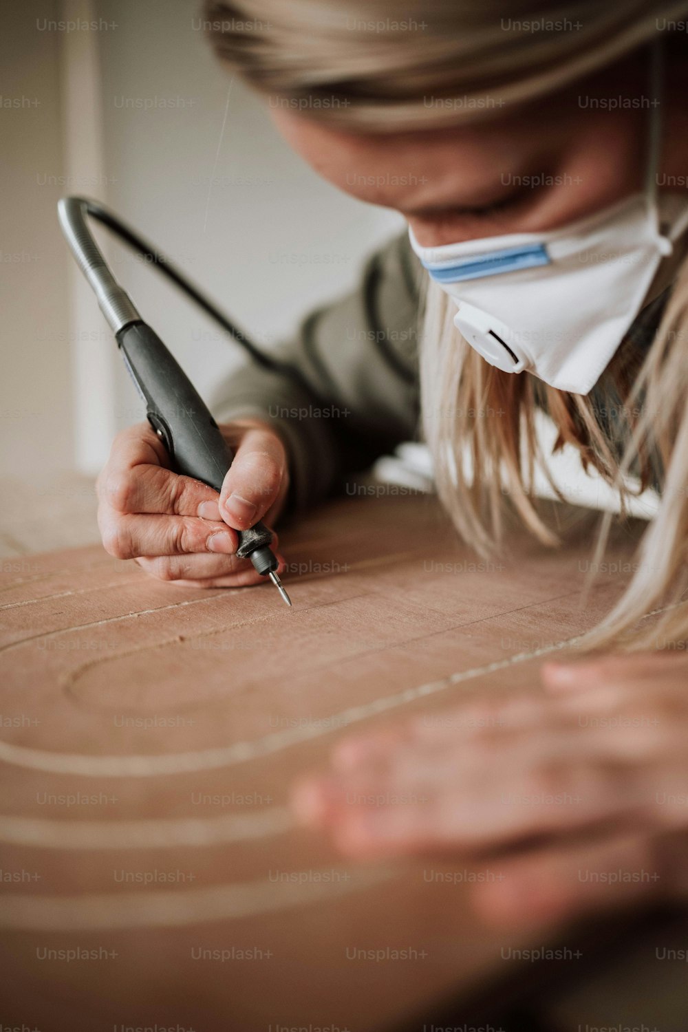 a woman wearing a face mask is cutting a piece of cardboard