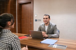 a man sitting at a desk with a laptop in front of him