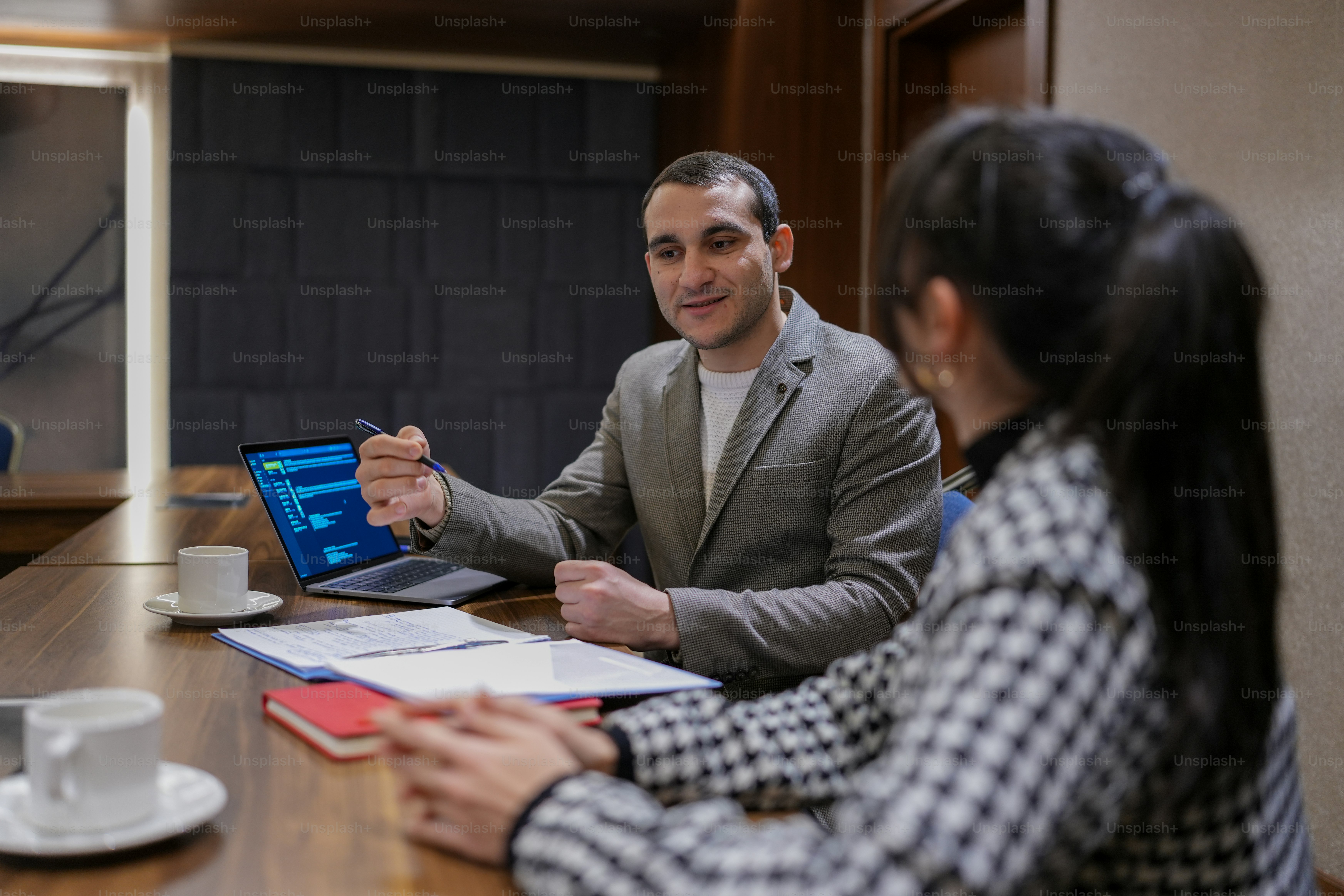 a man and woman sitting at a table with a laptop