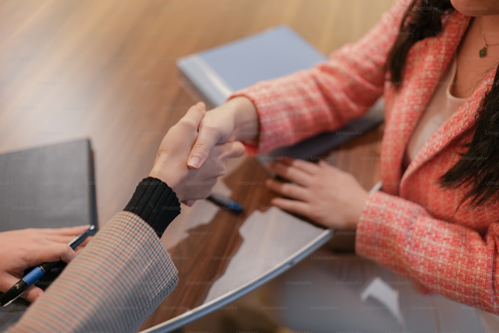 Deux personnes se serrant la main sur un bureau avec un ordinateur portable