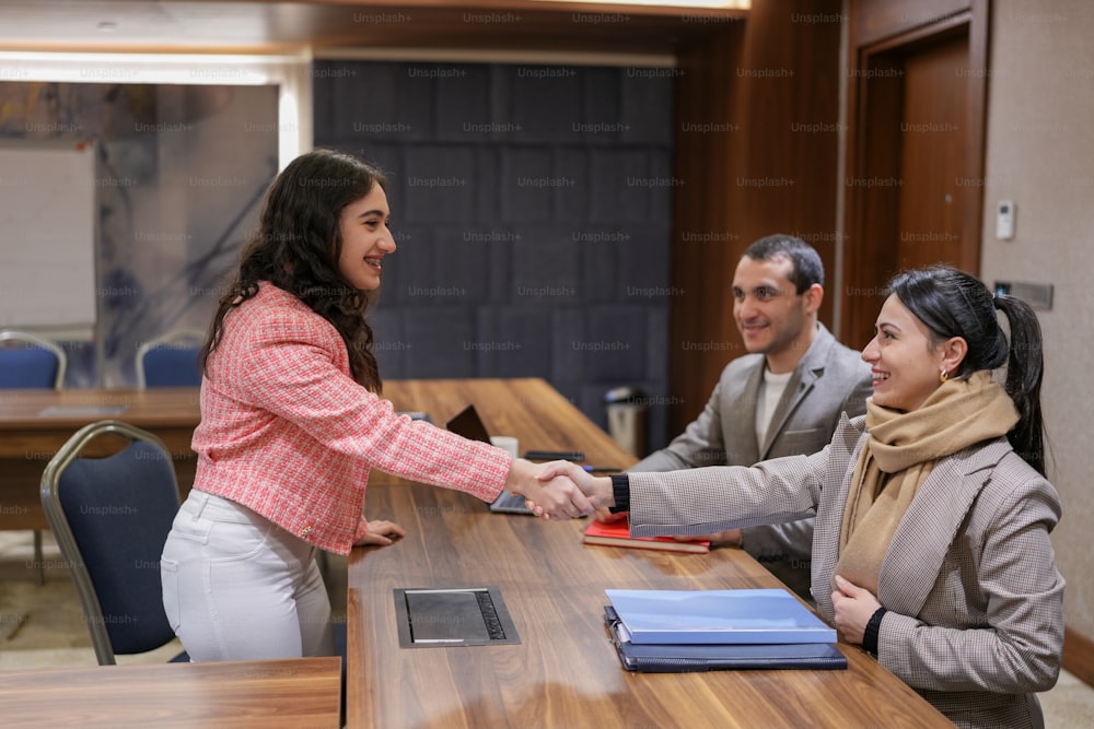 a woman shaking hands with a man at a table