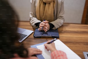 a woman sitting at a table writing on a piece of paper