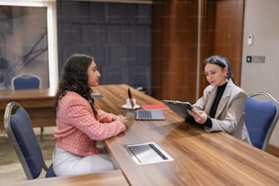 two women sitting at a table with a tablet