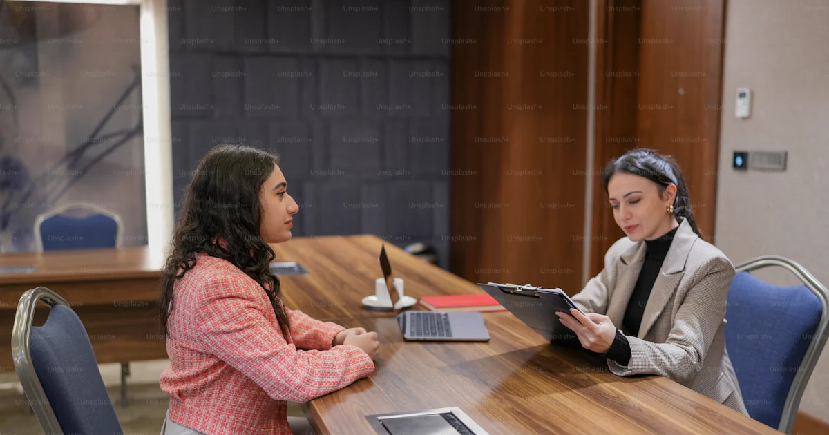 Two women sitting at a table with a tablet photo – Interview Image on ...