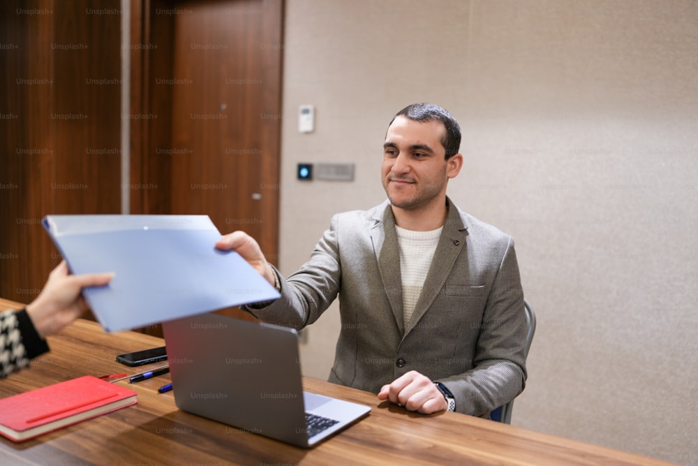 a man sitting at a desk in front of a laptop computer